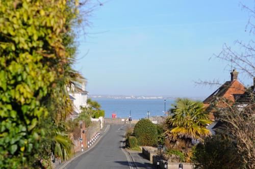 an empty street with houses and the ocean in the background at Red House in Seaview
