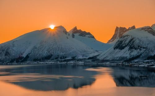 a snow covered mountain with the sun setting behind it at Skagi Bed & Lodge in Skaland