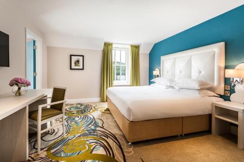 ein Hotelzimmer mit einem großen Bett und einem Schreibtisch in der Unterkunft The Daffodil Hotel & Spa in Grasmere