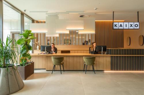 duas mulheres sentadas numa recepção no átrio em Leonardo Hotel San Sebastián em San Sebastián