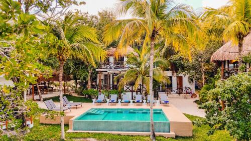 a swimming pool with palm trees and a house at Azulea Bacalar Hotel & Spa - Lagoon Front in Bacalar