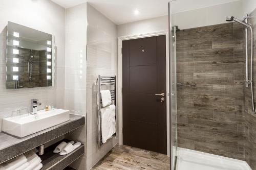 a bathroom with a sink and a glass shower door at The Daffodil Hotel & Spa in Grasmere