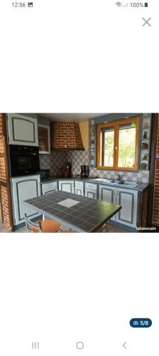 une cuisine avec une table et un comptoir dans l'établissement Chalet de L'étang, à Hargnies