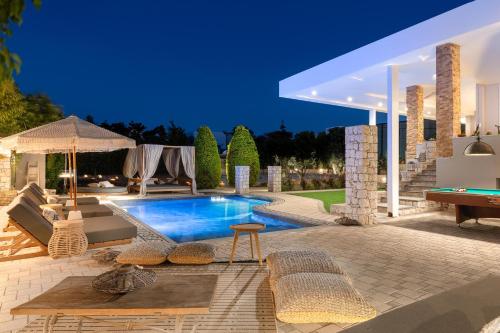 una piscina en un patio trasero con sillas y mesa en Vento Imperiale Estate en Rodas