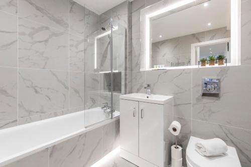 Baño blanco con aseo y lavamanos en Bright and spacious Apartment - Excellent Location en Londres