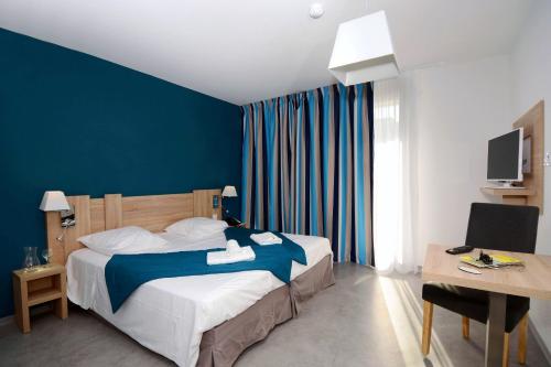 een slaapkamer met een bed en een blauwe muur bij Résidence Prestige Odalys Nakâra in Cap d'Agde