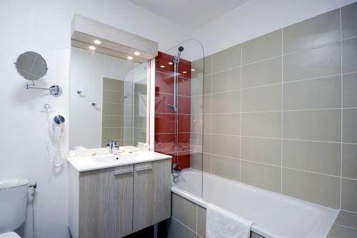 La salle de bains est pourvue d'un lavabo, d'une baignoire et de toilettes. dans l'établissement Résidence Prestige Odalys Nakâra, au Cap d'Agde