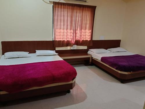 2 łóżka w pokoju z fioletową pościelą w obiekcie Aditya palace w mieście Shirdi