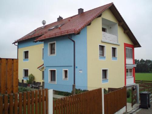 Wiesent的住宿－Vermietung Gisl，蓝色和黄色的房屋,设有围栏