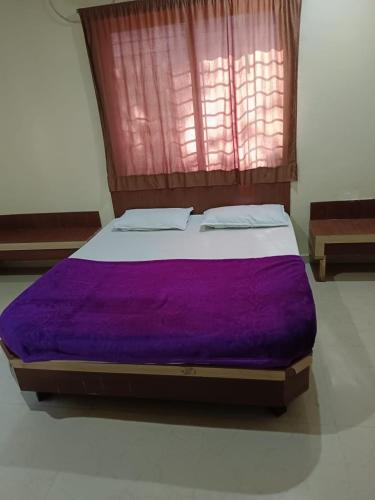duże łóżko z fioletową kołdrą w pokoju w obiekcie Aditya palace w mieście Shirdi