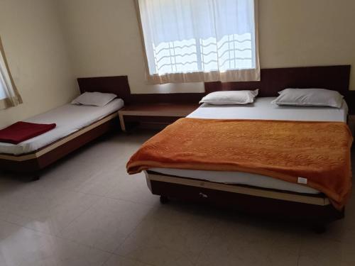dwa łóżka w pokoju z oknem w obiekcie Aditya palace w mieście Shirdi