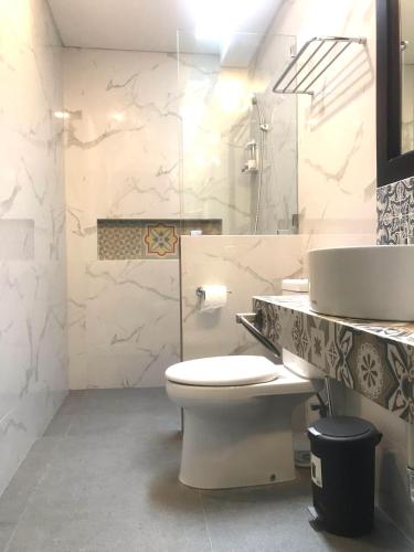 a white bathroom with a toilet and a sink at Rumah Kenyeri in Denpasar