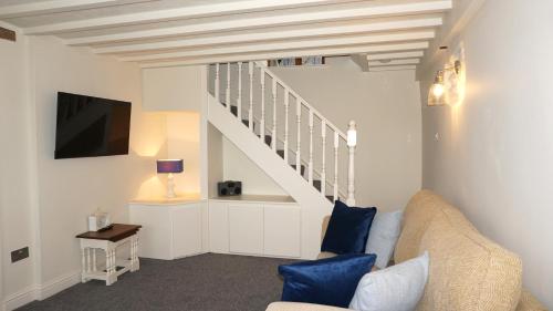 a living room with a couch and a staircase at Wheat Cottage - 5* Cyfie Farm with private covered hot tub in Llanfyllin