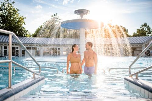 Ein Mann und eine Frau stehen im Wasser im Pool in der Unterkunft ...mein Graml in Bad Füssing