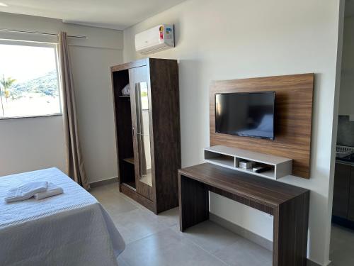 a bedroom with a tv and a bed and a table at Condomínio Kaimã in Matinhos
