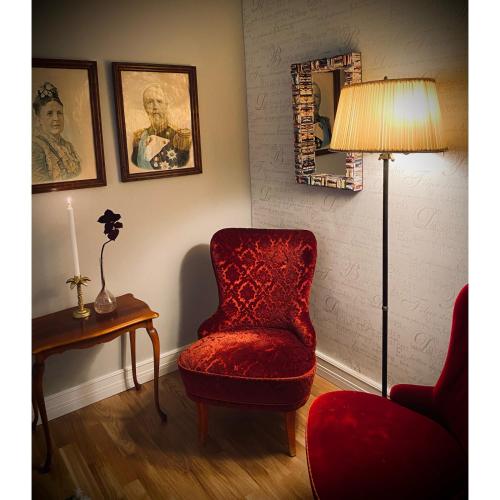 a living room with a red chair and a lamp at Villa Sol B&B and Hostel in Borgholm