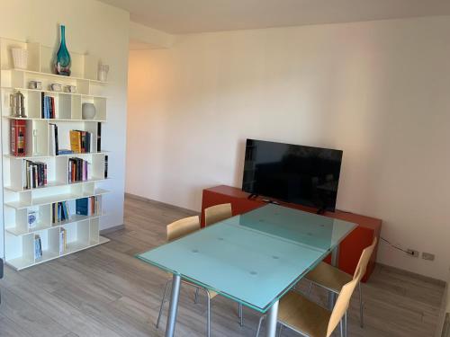 - un salon avec une table, une télévision et une étagère dans l'établissement Appartamento Du Lac, à Baveno