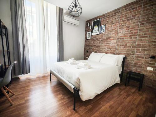 1 dormitorio con 1 cama grande y pared de ladrillo en Urban Holiday, en Roma
