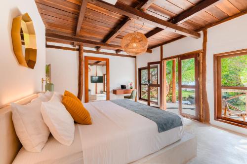 um quarto com uma grande cama branca e janelas em Hotel Azulea Bacalar - Lagoon Front em Bacalar