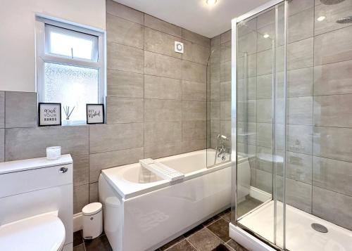 a bathroom with a tub and a toilet and a shower at Homely 4-bedroom House in Manchester