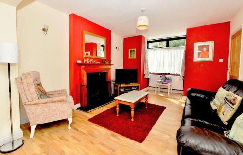 a living room with red walls and a couch and a table at Pembroke Villa in Shanklin