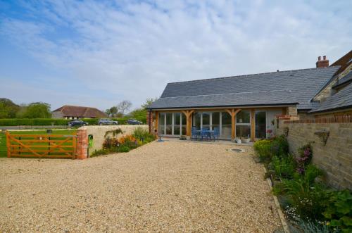 a barn conversion with a patio and a house at The Poppies in Brighstone