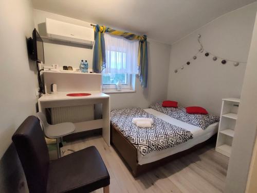 a small bedroom with a bed and a chair at Stajnia pod Dębem in Starachowice