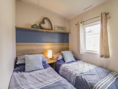 two beds in a small room with a window at Seasalt in West Mersea