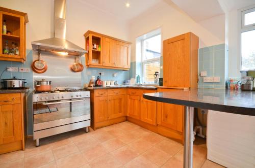 uma cozinha com armários de madeira e um forno com placa de fogão em St Georges Villa em Ryde
