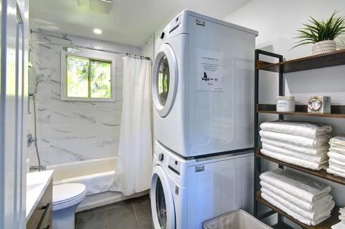a washer and dryer in a bathroom with a tub at Waterfront - Chalet des Becassines in Nominingue