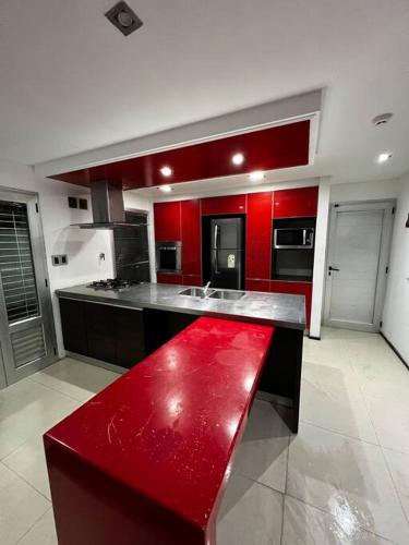un banco rojo en una gran cocina con armarios rojos en Hermosa y amplia casa en Roldán en Roldán