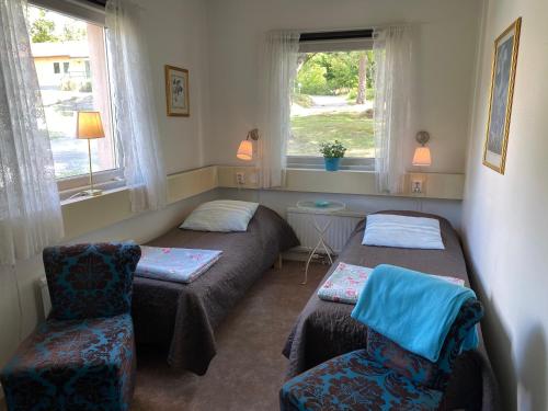 a room with two beds and a chair and windows at Bogesund Slottsvandrarhem in Vaxholm