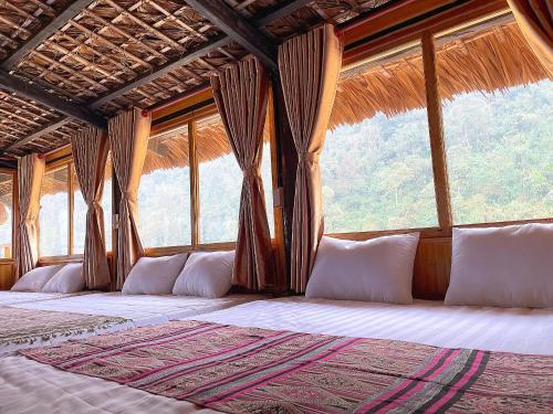 Cama en habitación con ventanas grandes en Ngũ Chỉ Sơn Trekking Sapa en Sa Pa