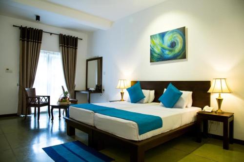 una camera da letto con un grande letto con cuscini blu di Rathna Beach Wadduwa a Kalutara