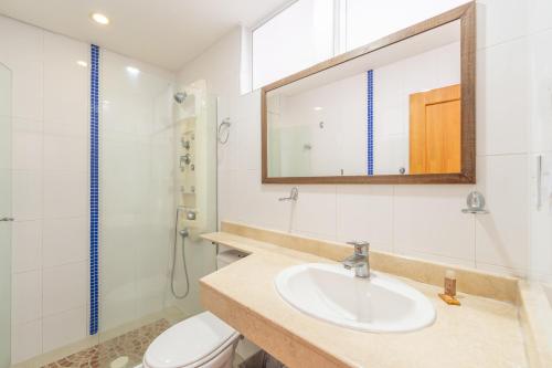 a bathroom with a sink and a toilet and a mirror at Basic Hotel Centenario by Hoteles MS in Cali