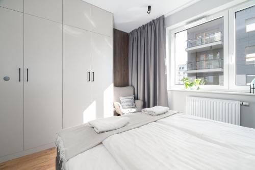 a white bedroom with a large bed and a window at Apartament przy Koscielnej in Poznań