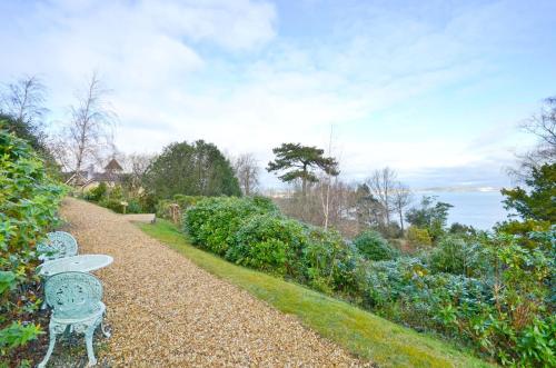 a gravel path with two benches in a garden at Stunning Ocean Views, The Priory in Shanklin