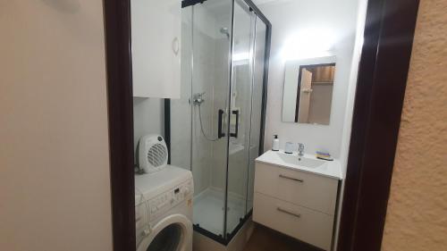 une salle de bain avec douche et lavabo et une machine à laver dans l'établissement Le studio rêves bleus, à La Grande Motte