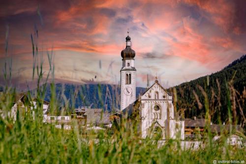 Una iglesia con una torre con un reloj. en Appartement STAUDEN, en Innervillgraten