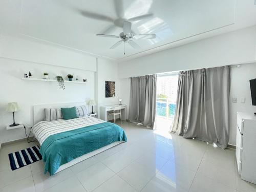 1 dormitorio blanco con 1 cama y ventilador de techo en Elegante Aqua Marine Apartamento en Playa Juan Dol, en Juan Dolio