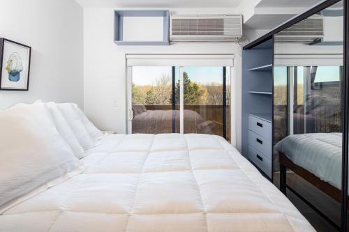 1 cama blanca grande en un dormitorio con ventana en Micro Boutique Living Fredericton, en Fredericton