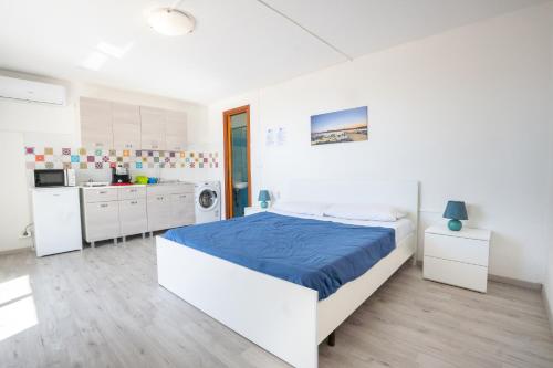 een witte slaapkamer met een bed en een keuken bij Camera Ponente - vista mare, spiaggia a 300m in Golfo Aranci