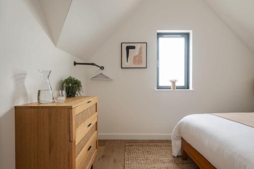 a bedroom with a bed and a dresser and a window at The Penthouse in Hope-Cove