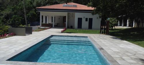 a swimming pool in front of a house at Fazenda São Miguel in Monte Alegre do Sul