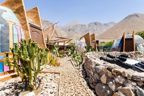 un grupo de casas con cactus y una pared de piedra en Hostal Cosmo Elqui, en Rivadavia
