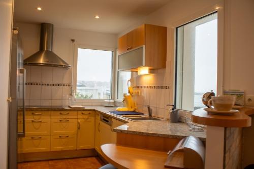 une cuisine avec des armoires jaunes et une grande fenêtre dans l'établissement Ti Ma Zud/Vue mer/Wifi, à Camaret-sur-Mer