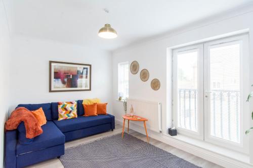 a living room with a blue couch and a window at Charming 3- Bedroom Terrace House with Netflix and Free Parking by HP Accommodation in Market Harborough
