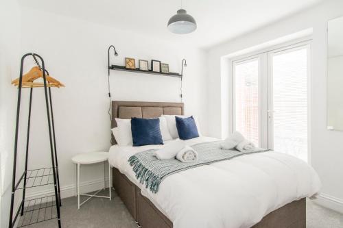 a bedroom with a large bed with blue pillows at Charming 3- Bedroom Terrace House with Netflix and Free Parking by HP Accommodation in Market Harborough