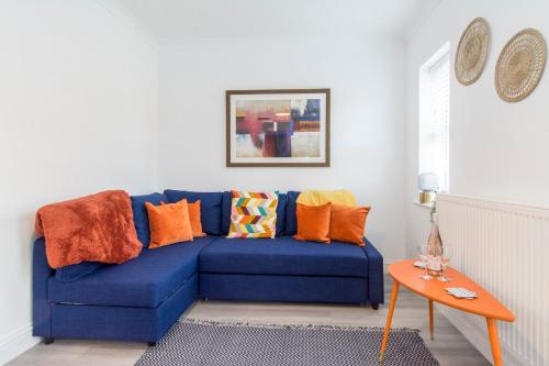 a blue couch with colorful pillows in a living room at Charming 3- Bedroom Terrace House with Netflix and Free Parking by HP Accommodation in Market Harborough