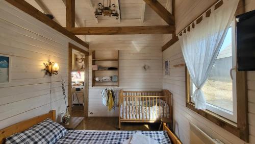 sypialnia z łóżeczkiem dziecięcym w pokoju z drewnianymi ścianami w obiekcie Casuta Schiorului 2, Mărișel Apuseni w mieście Mărişel